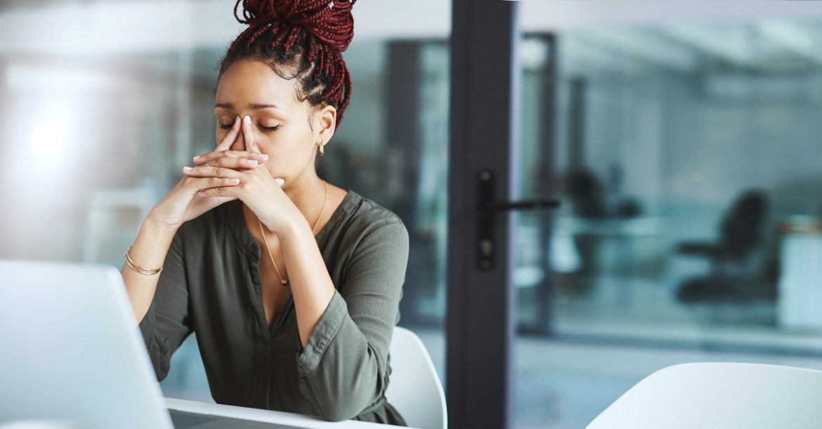 Fatigued female worker behind her laptop computer