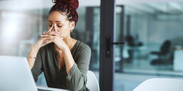 Fatigued female worker behind her laptop computer