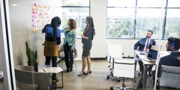 Colleagues in the meeting room standing by the kanban wall