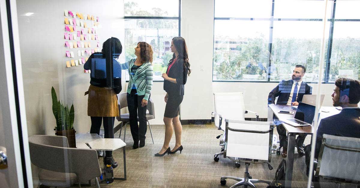 Colleagues in the meeting room standing by the kanban wall