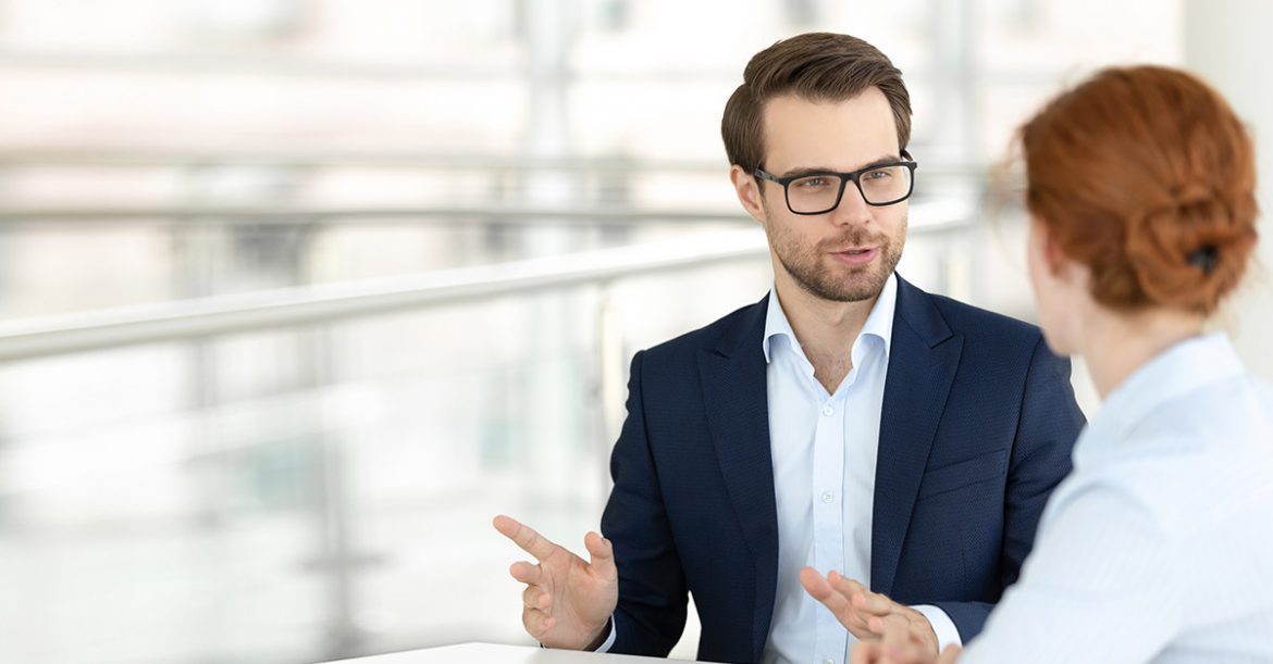 Smiling male office worker talking with female colleague