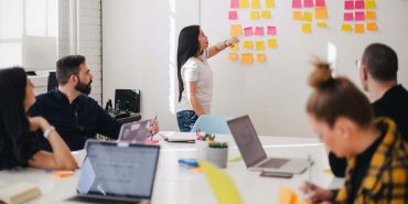 Casually dressed colleagues in the boardroom looking at the kanban wall