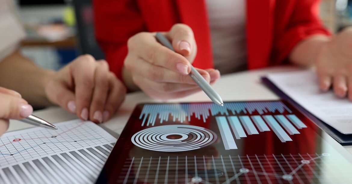 Business women studying charts and diagrams on digital tablet closeup