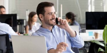 Smiling friendly man talking on phone in office