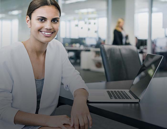 Ethnic businesswoman at desk with laptop in modern office