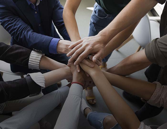 Top view hands stacked together as symbol of teambuilding