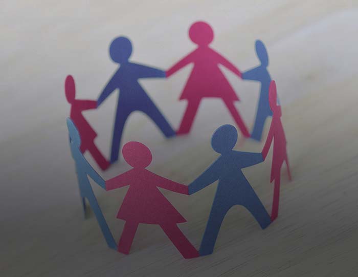 Paper men and women cut-out in a circle holding hands