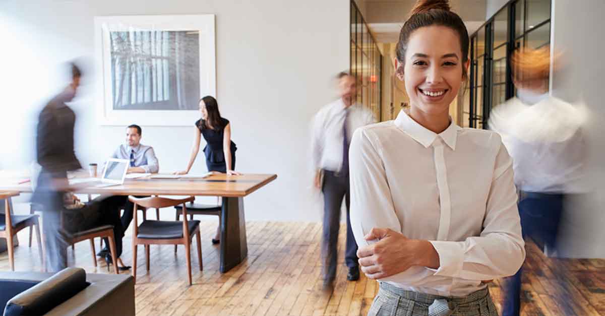 Portrait of young white woman in a busy modern workplace
