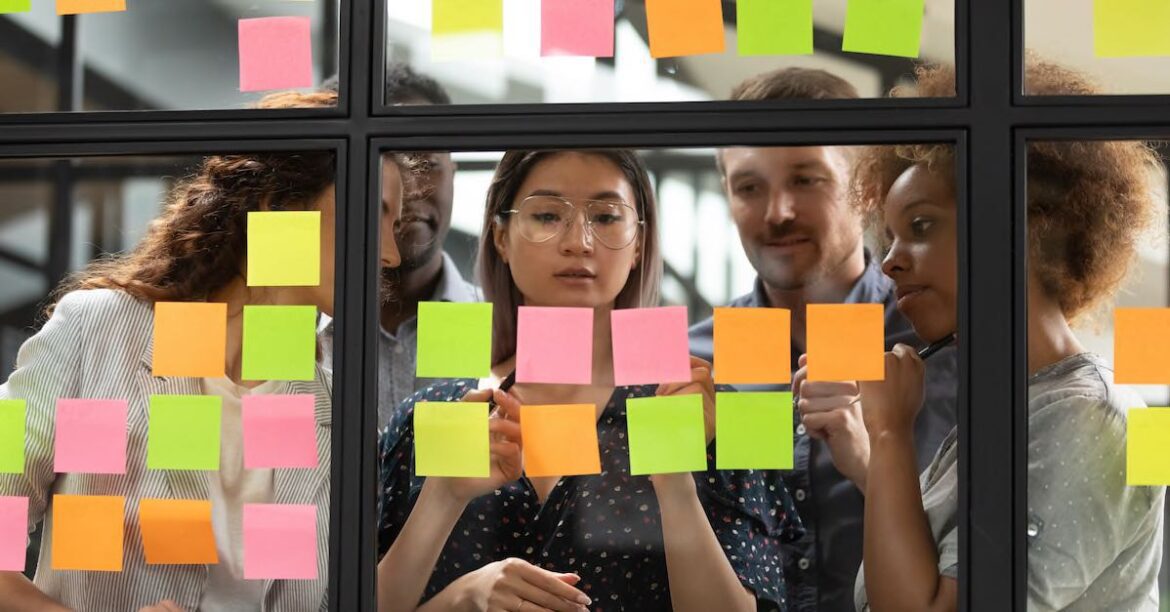 Team of five collaborating with post-it notes on an internal window