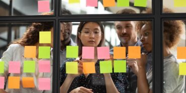Team of five collaborating with post-it notes on an internal window