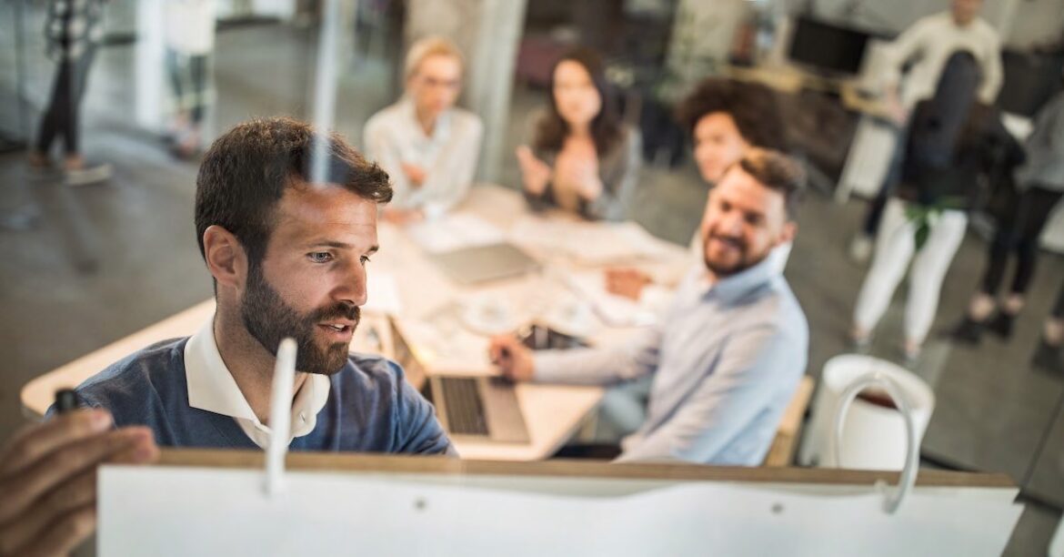 Team at table with team member standing at whiteboard